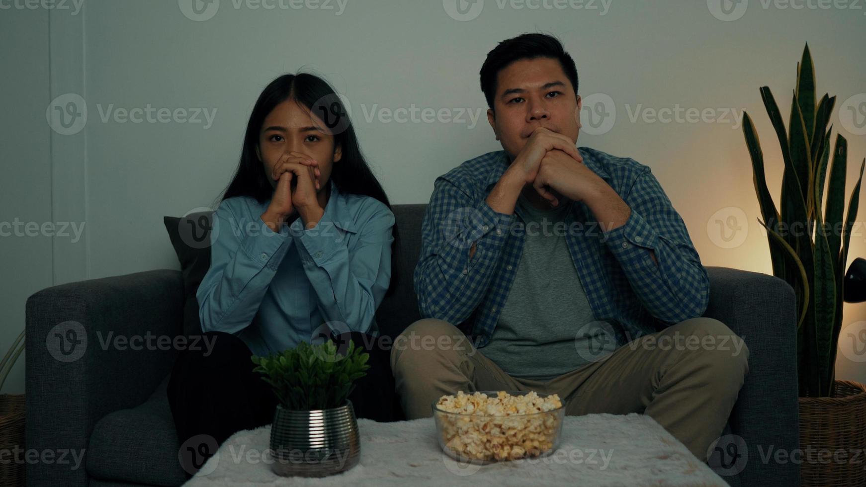 Asian couple in the living room watch a horror movie in the middle of the night. photo