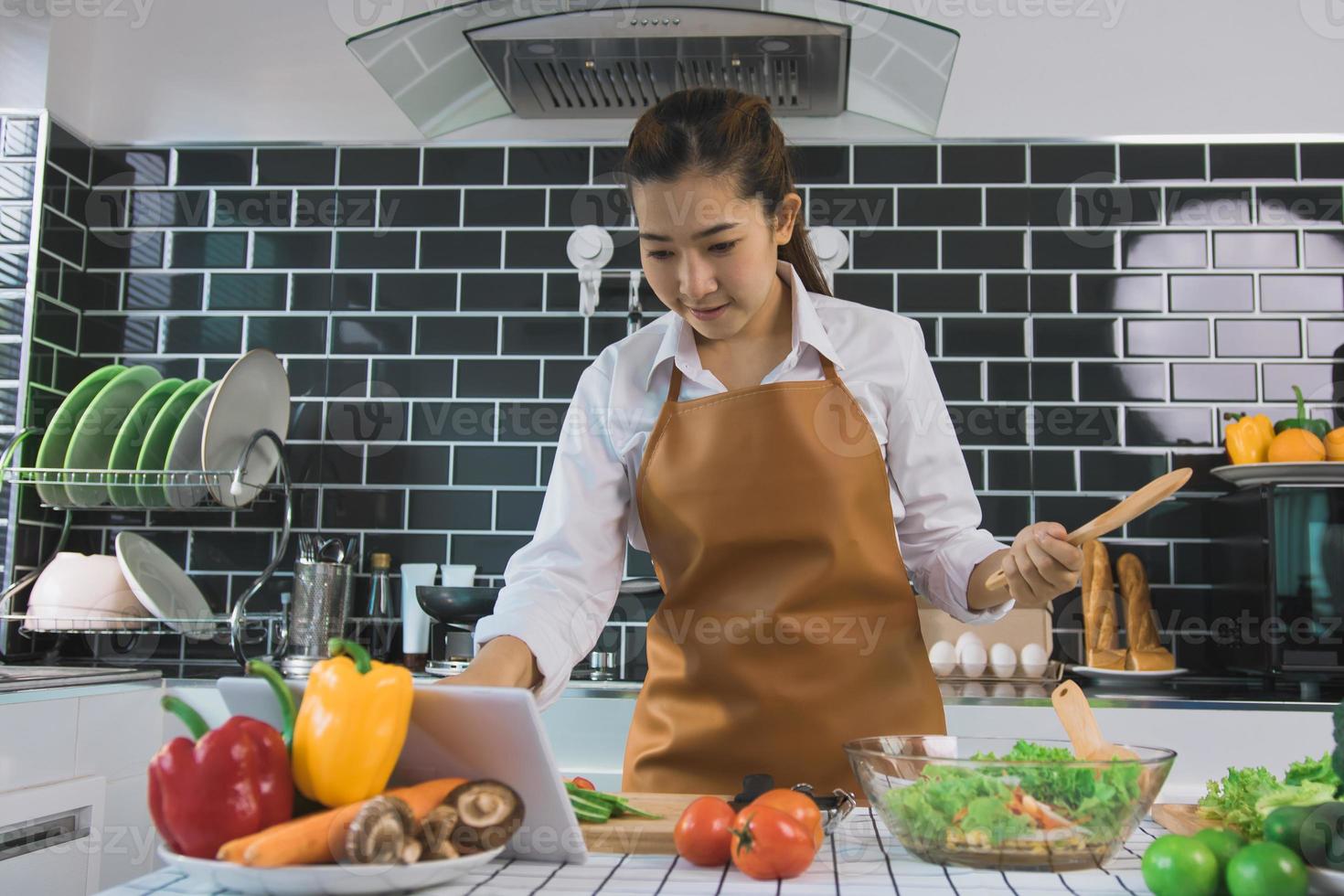 Asian women are using tablets to find recipes from cooking websites at the table. photo