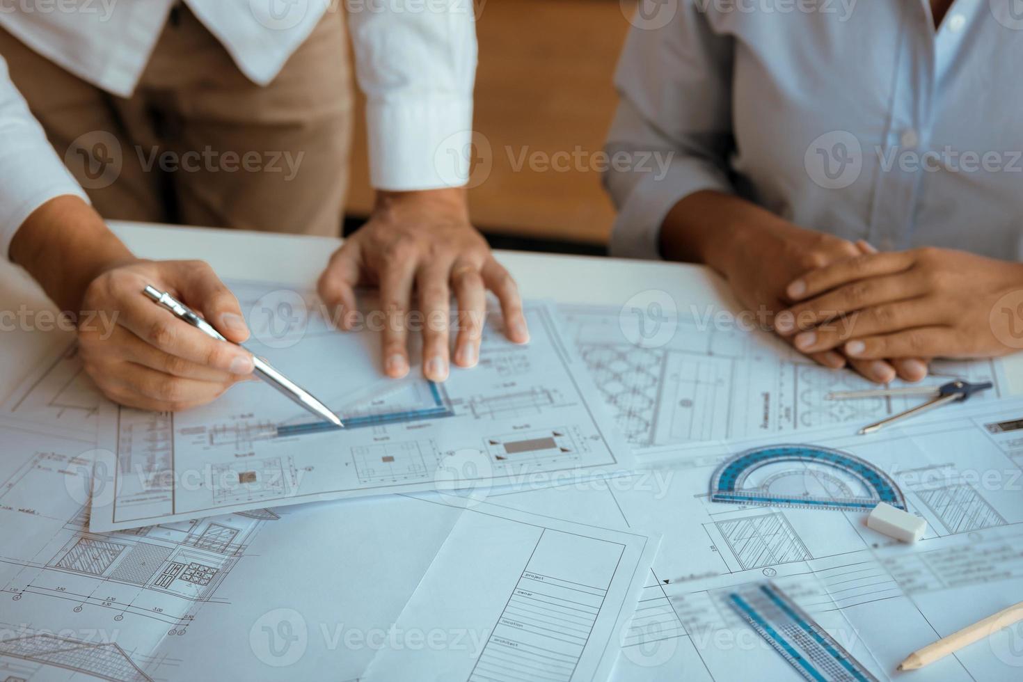 Architects engineer working with blueprints on table and discussing project together at the meeting in the office. photo