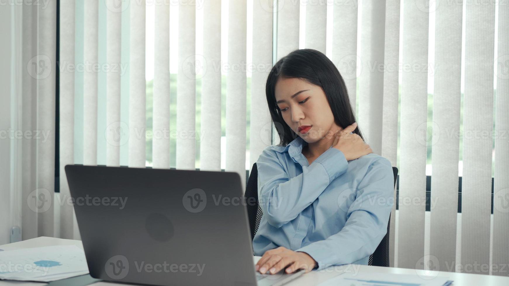 Asian woman working for a long time had pain in her shoulder while gently massaging her hand. photo