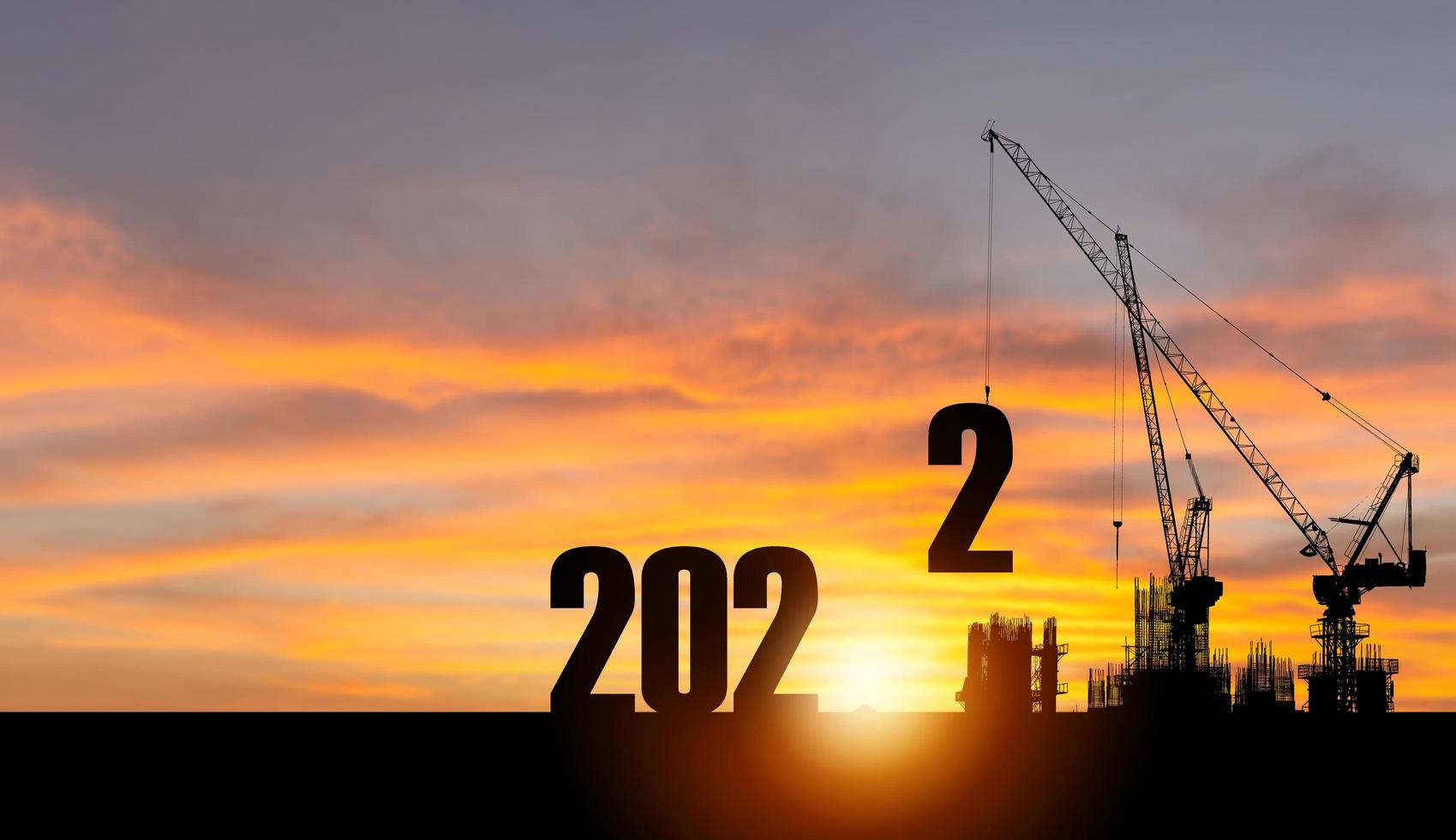 silueta del sitio de construcción con grúa y cielo de puesta de sol para la preparación del nuevo año de 2022 foto