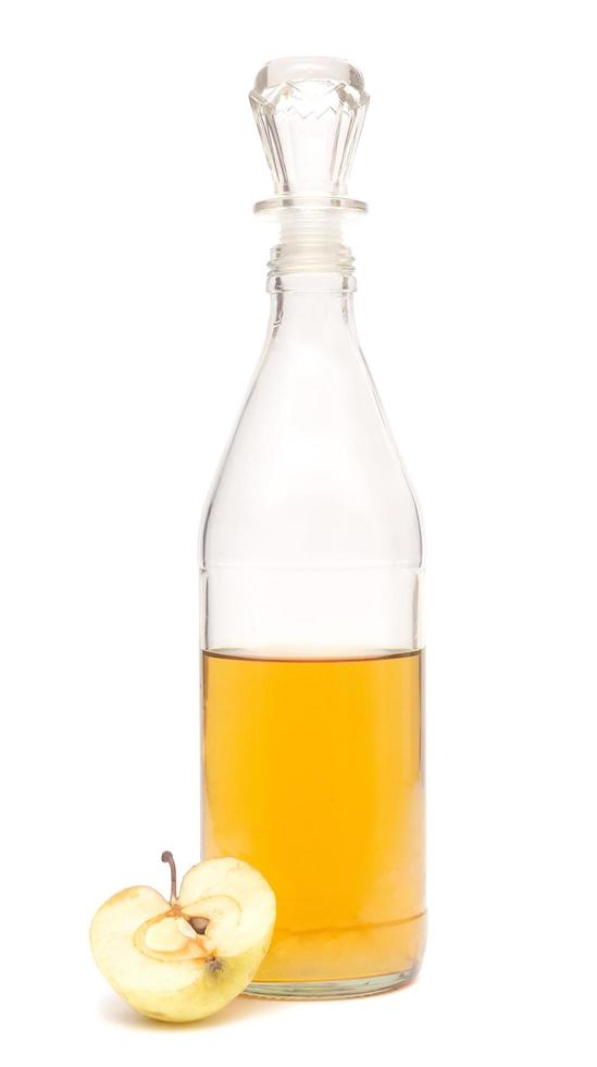 a half-filled bottle of apple cider vinegar and half an apple isolated on white background photo