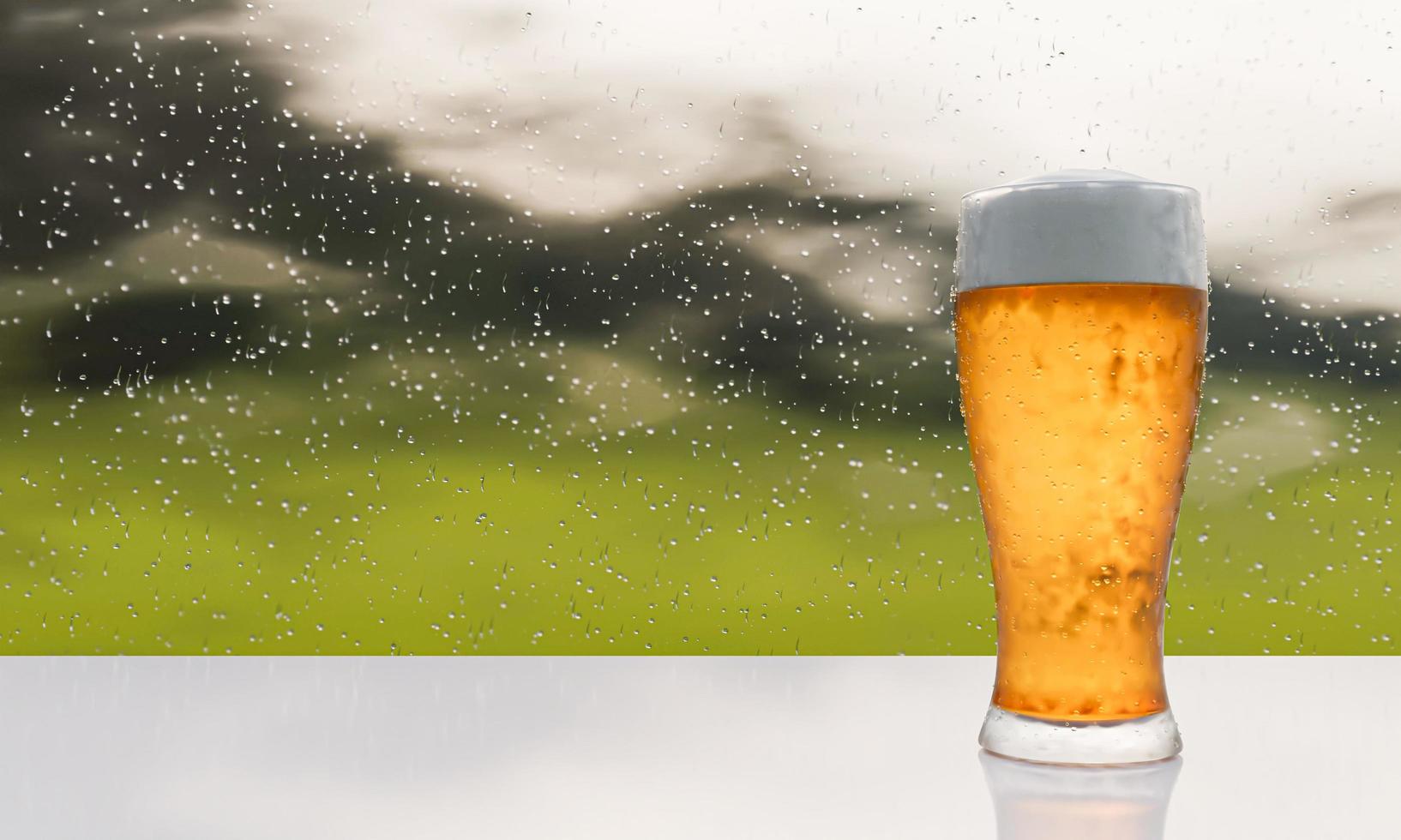 Cold draft beer in tall clear glass. The top is beer foam. There are water droplets on the glass. Place on a white surface table. the scenery outside the rain There is water droplets on the glass. photo