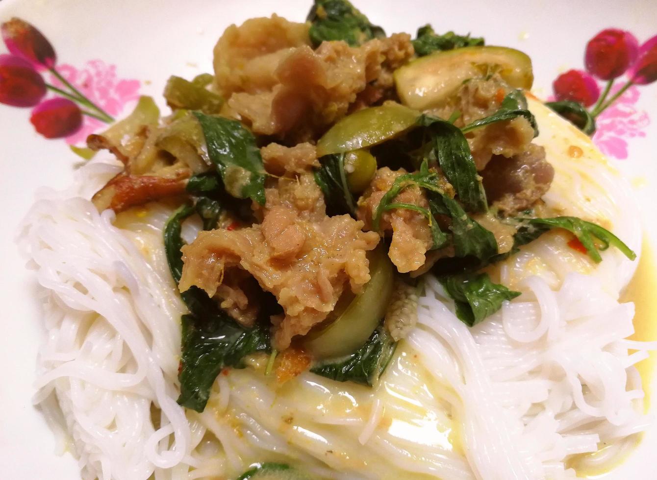 Rice noodles in green curry with beef. Traditional Thai food consisting of beef, eggplant, eggplant, basil leaves, and curry paste photo