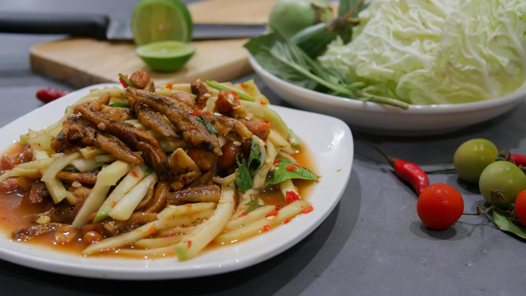 Yum, mango photo top views Food arrangement. Spicy salad food, topped with fried nuts and crispy fish. The main ingredients are raw mango, lime juice, fresh chili powder, fish sauce, sugar to mix.