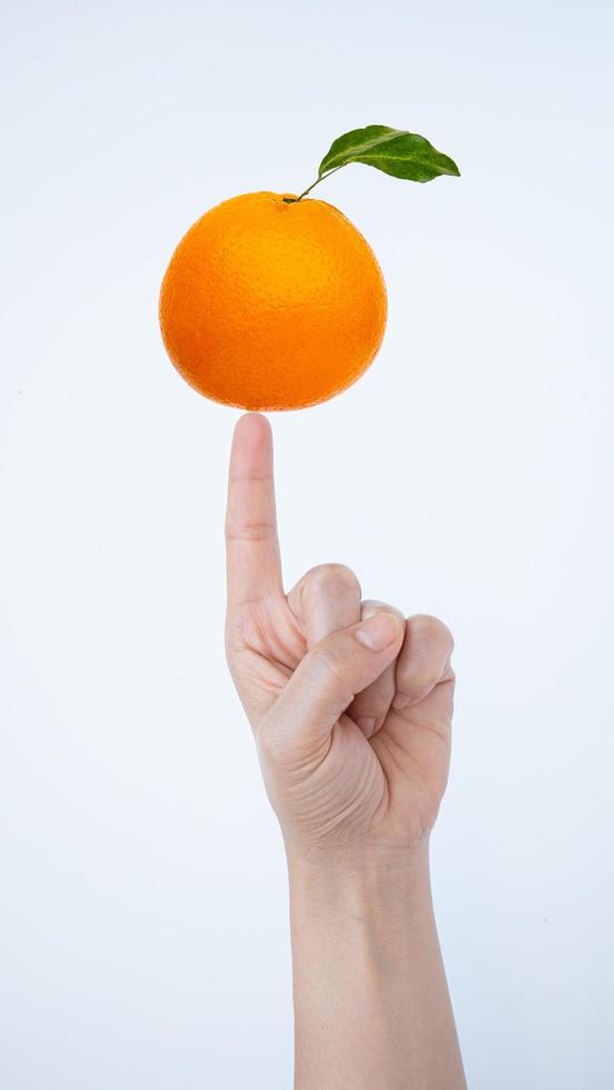 Female hand pointing up There is a ripe orange on the finger. Isolated on a white background. photo