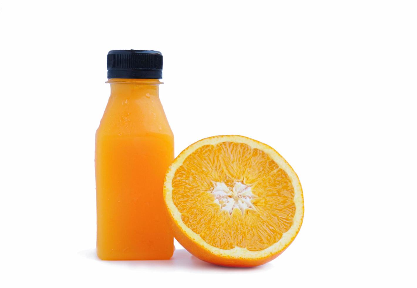 A bottle full of orange juice and a half-cut citrus leaning against the orange juice bottle on a white background. photo