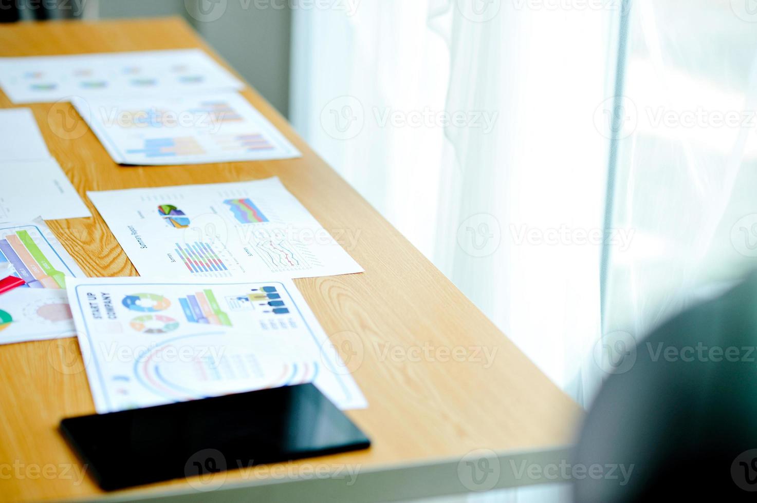 Wooden desk in sunny office with large windows Have a document placed next to it. With black phone The desk of the businessman. photo