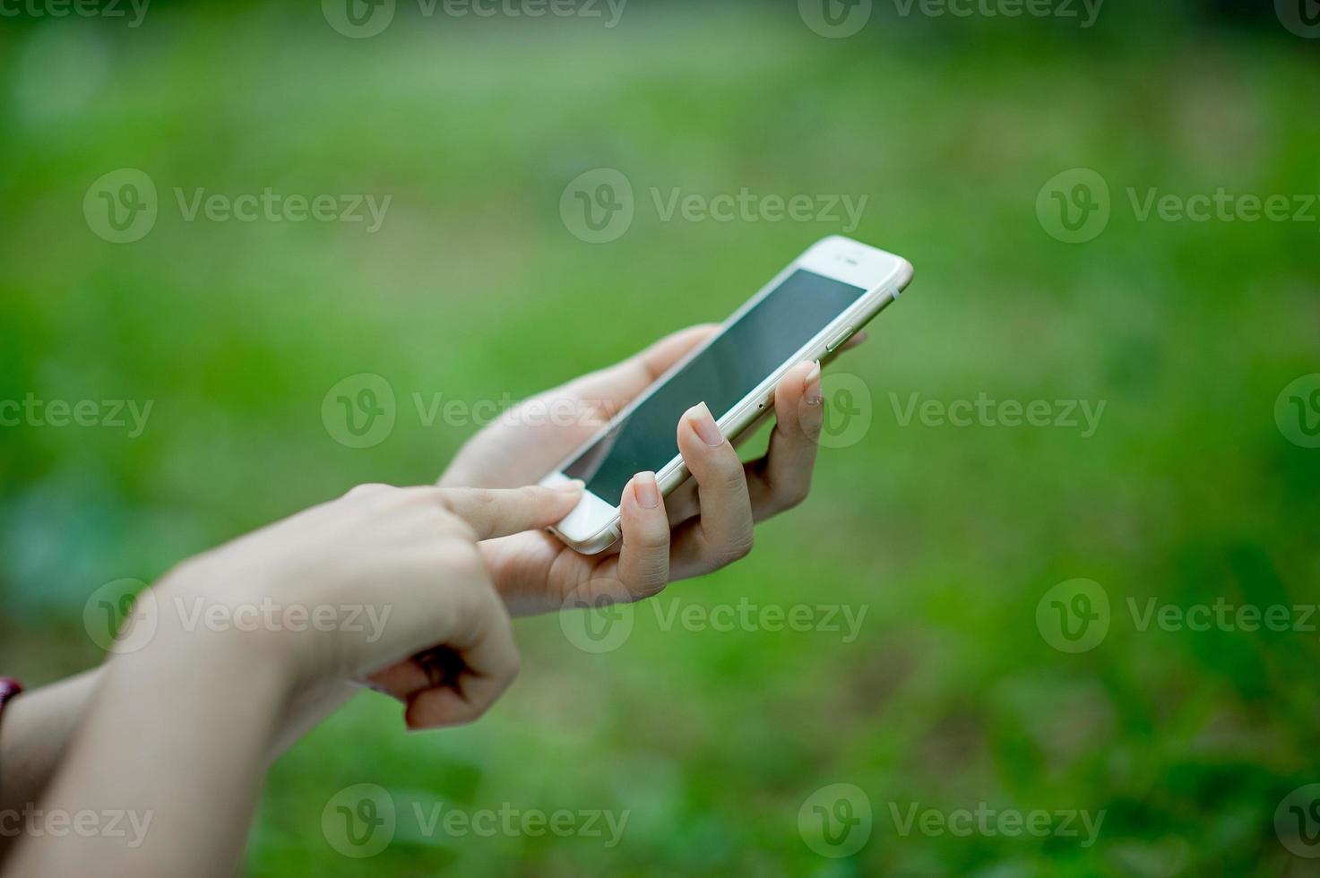 Girl playing phone on hand for online communication and contact Wear red shirt and green background And there is a copy space. photo