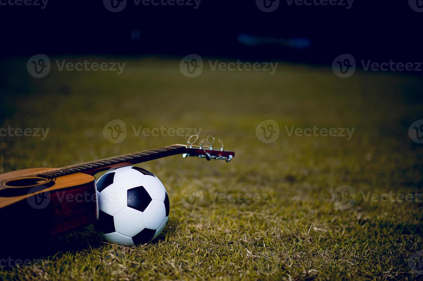 la guitarra y el fútbol se colocan en céspedes verdes. ideas de música y deportes y hay un espacio de copia. foto