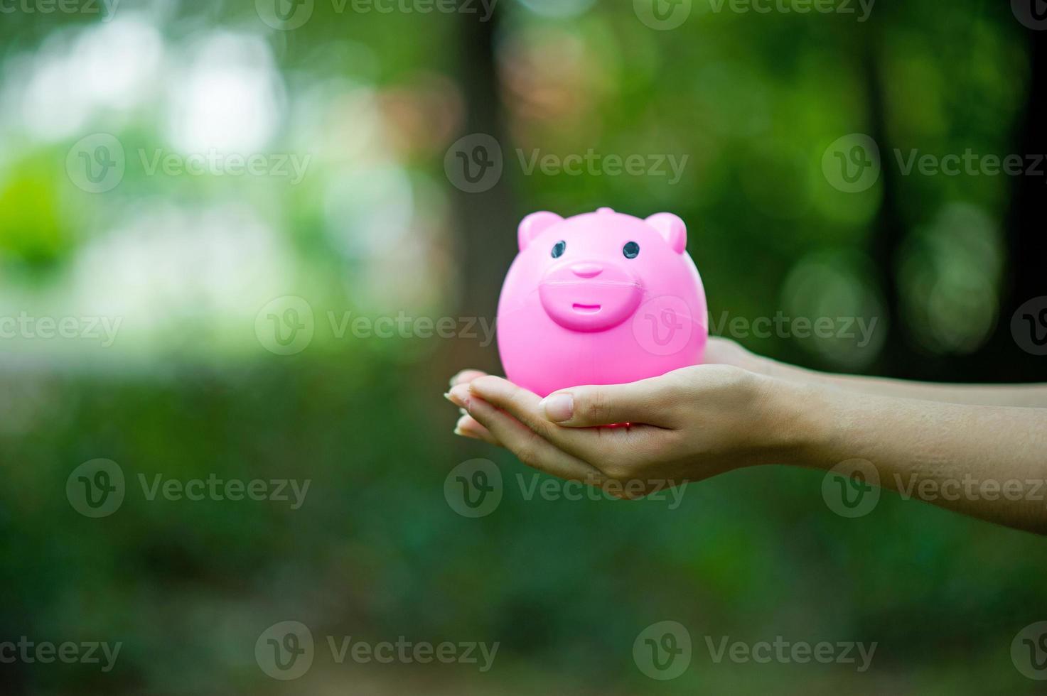 mano femenina sosteniendo alcancía rosa, alcancía y feliz con los ahorros. y copiar espacio foto