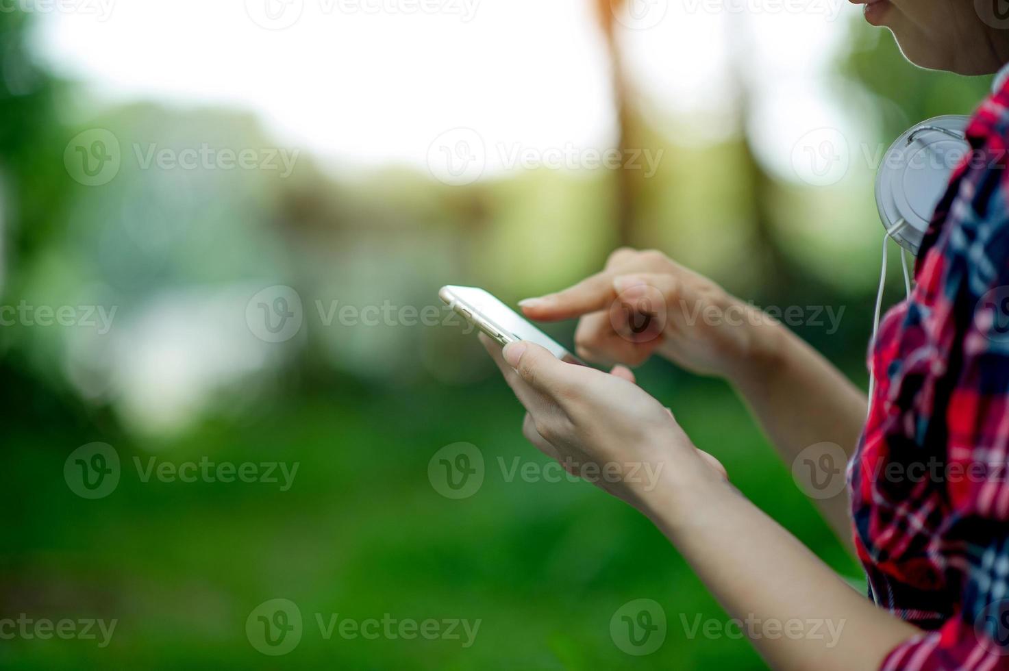 niña jugando teléfono a mano para comunicación en línea y contacto use camisa roja y fondo verde y hay un espacio de copia. foto