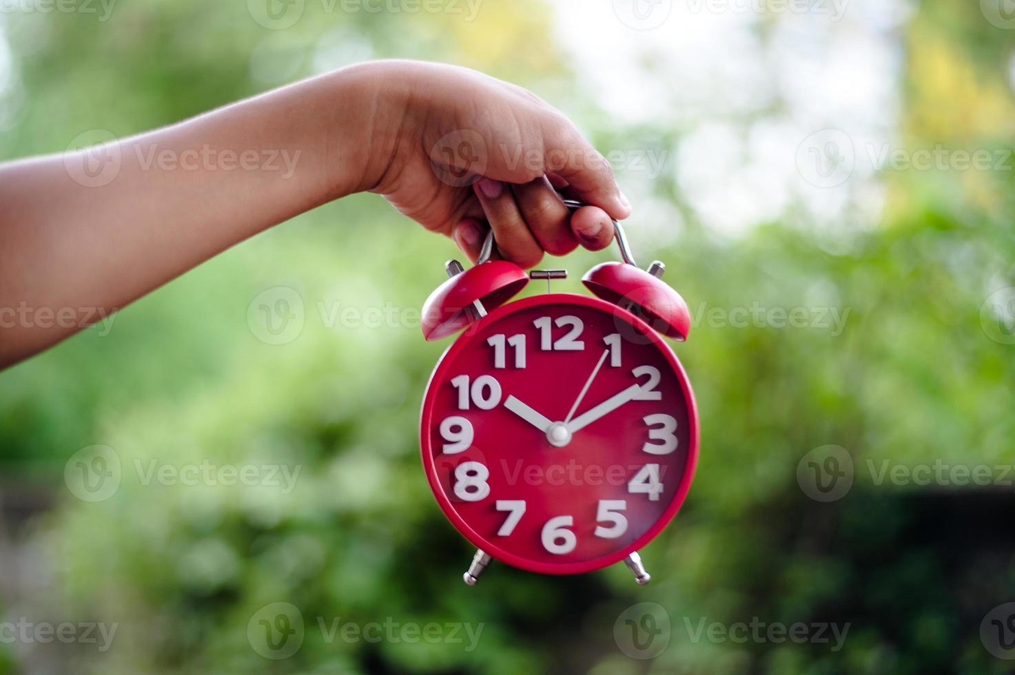 Creative flat flat concept Top view of a man's hand holding an antique red alarm clock on a bright green background with turquoise, with the smallest available copy space. photo