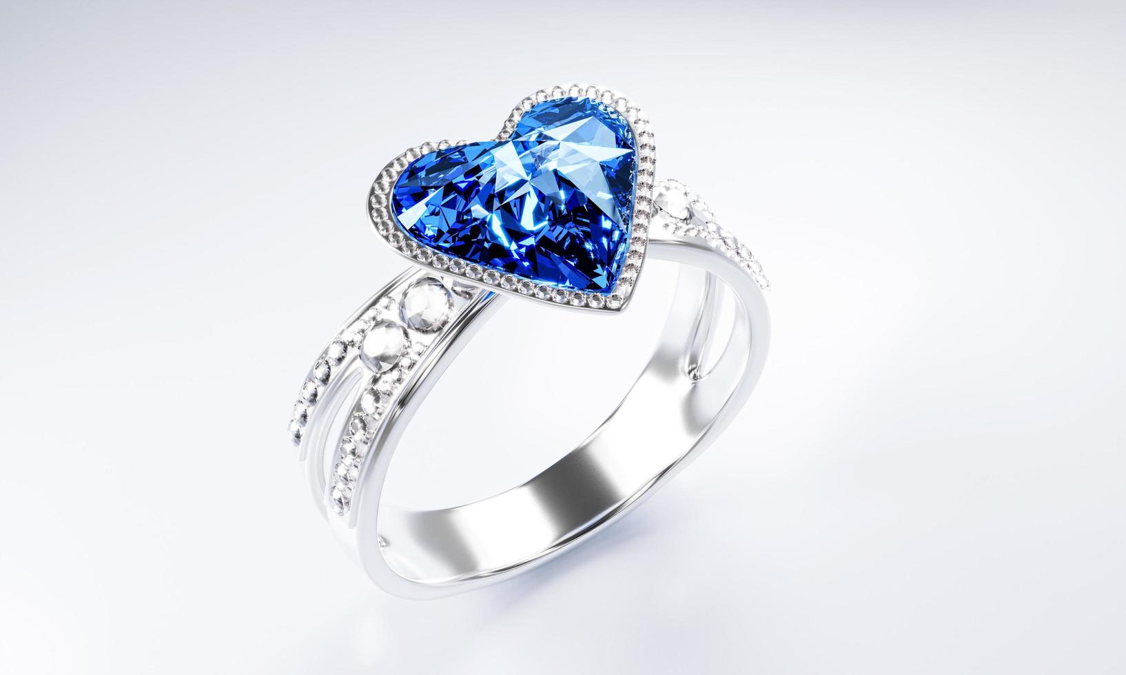 The large blue diamond heart shape is surrounded by many diamonds on the ring made of platinum gold placed on a gray background. Elegant wedding diamond ring for women.  3d rendering photo