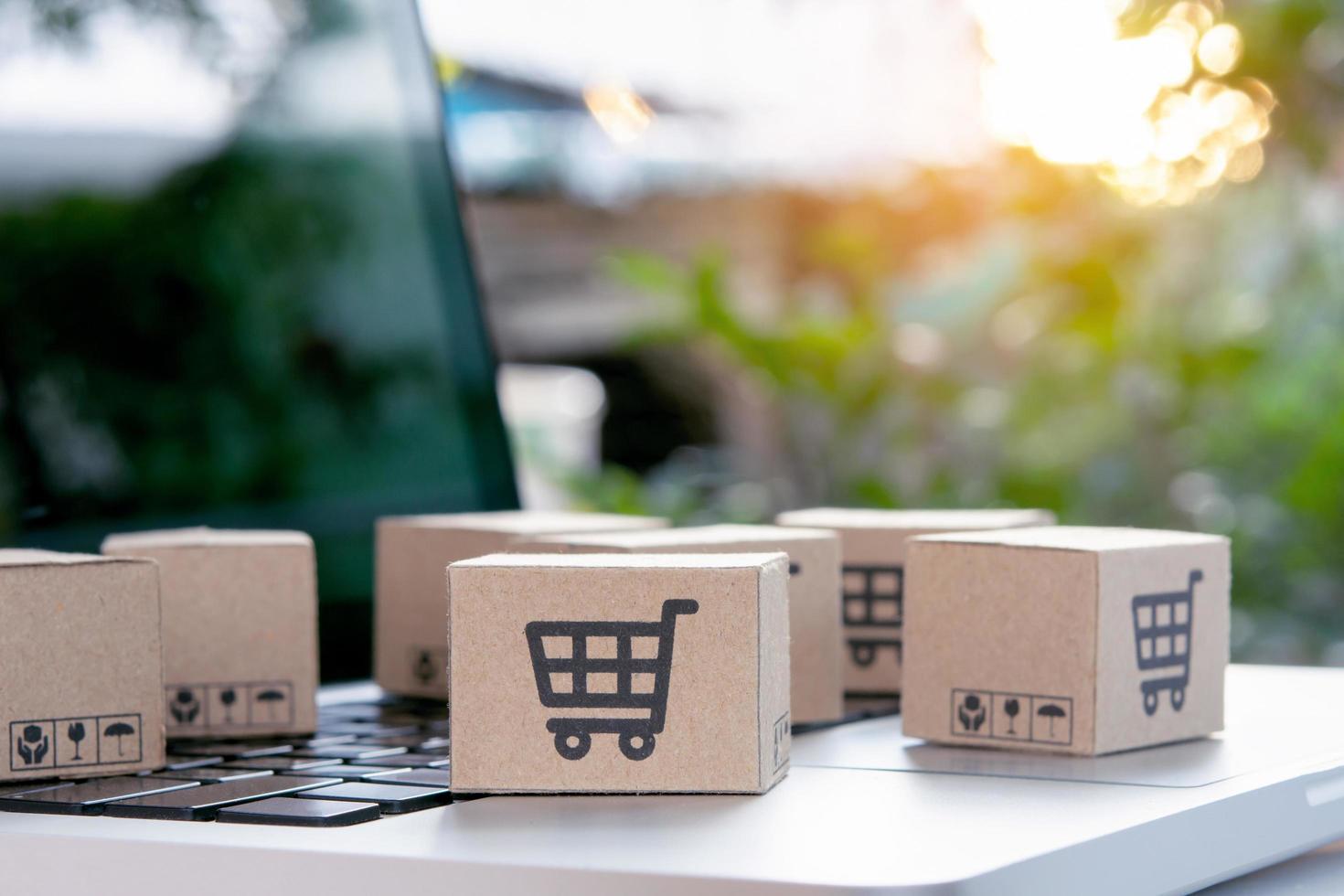 Online shopping - Paper cartons or parcel with a shopping cart logo on a laptop keyboard. Shopping service on The online web and offers home delivery. photo