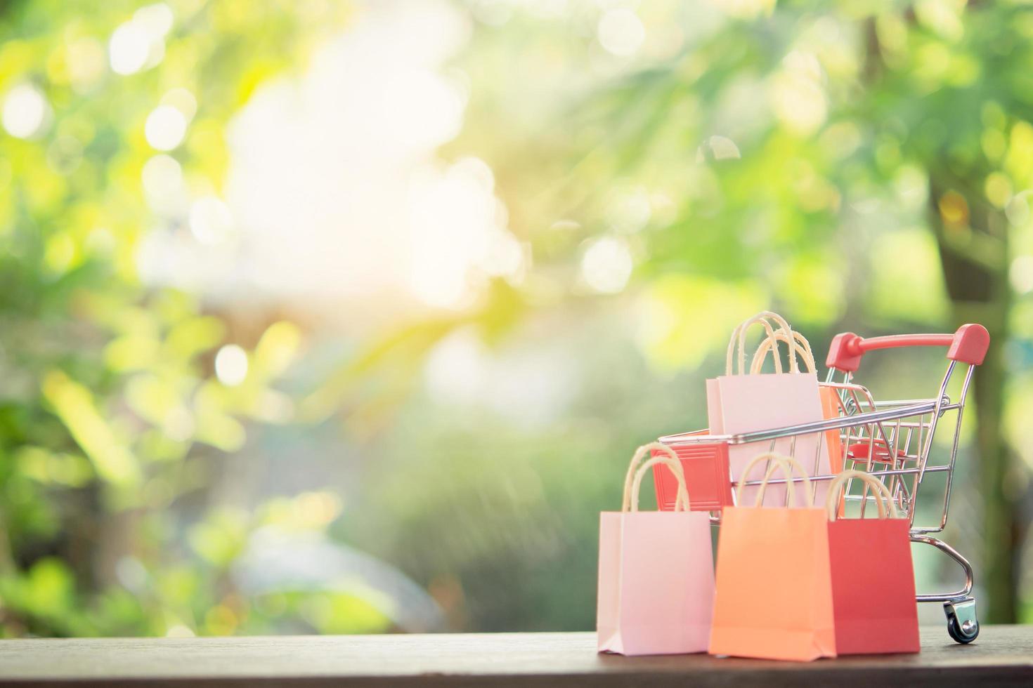 Shopping concept - Shopping cart or trolley, Shopping bags on wood table. online shopping consumers can shop from home and delivery service. with copy space photo