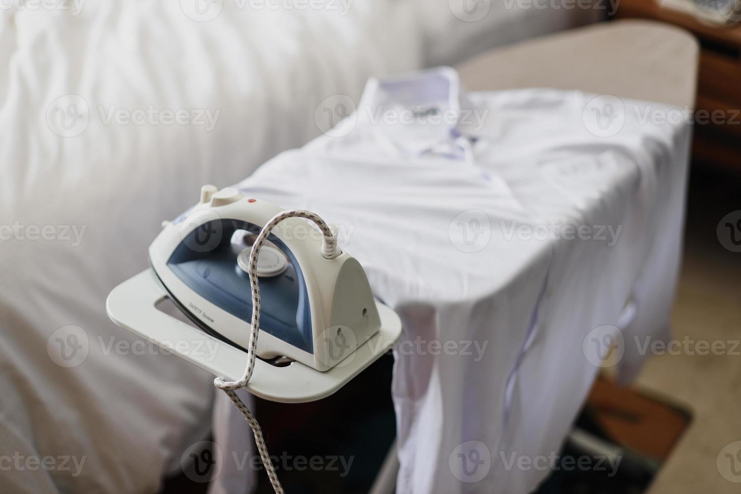 Modern iron and white shirt on ironing board photo