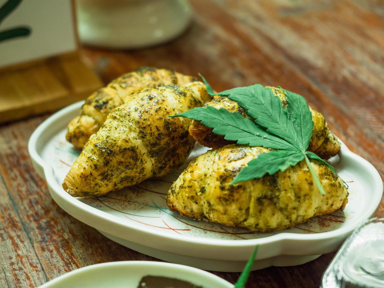 Croissants mix dried cannabis power and decorated with fresh leaf. photo
