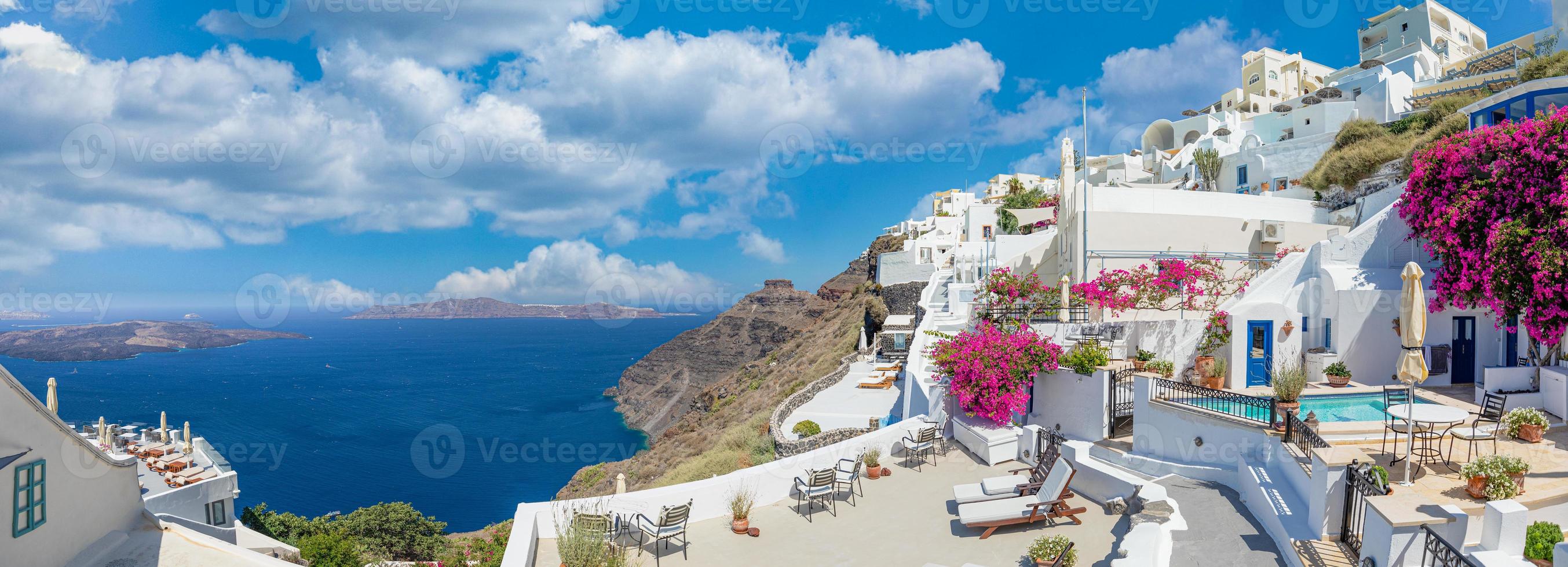 ciudad de oia en la isla de santorini, grecia. casas tradicionales blancas y azules famosas con flores bajo un clima soleado sobre la caldera, mar Egeo. hermoso paisaje de verano, vista al mar, vacaciones de viaje de lujo foto