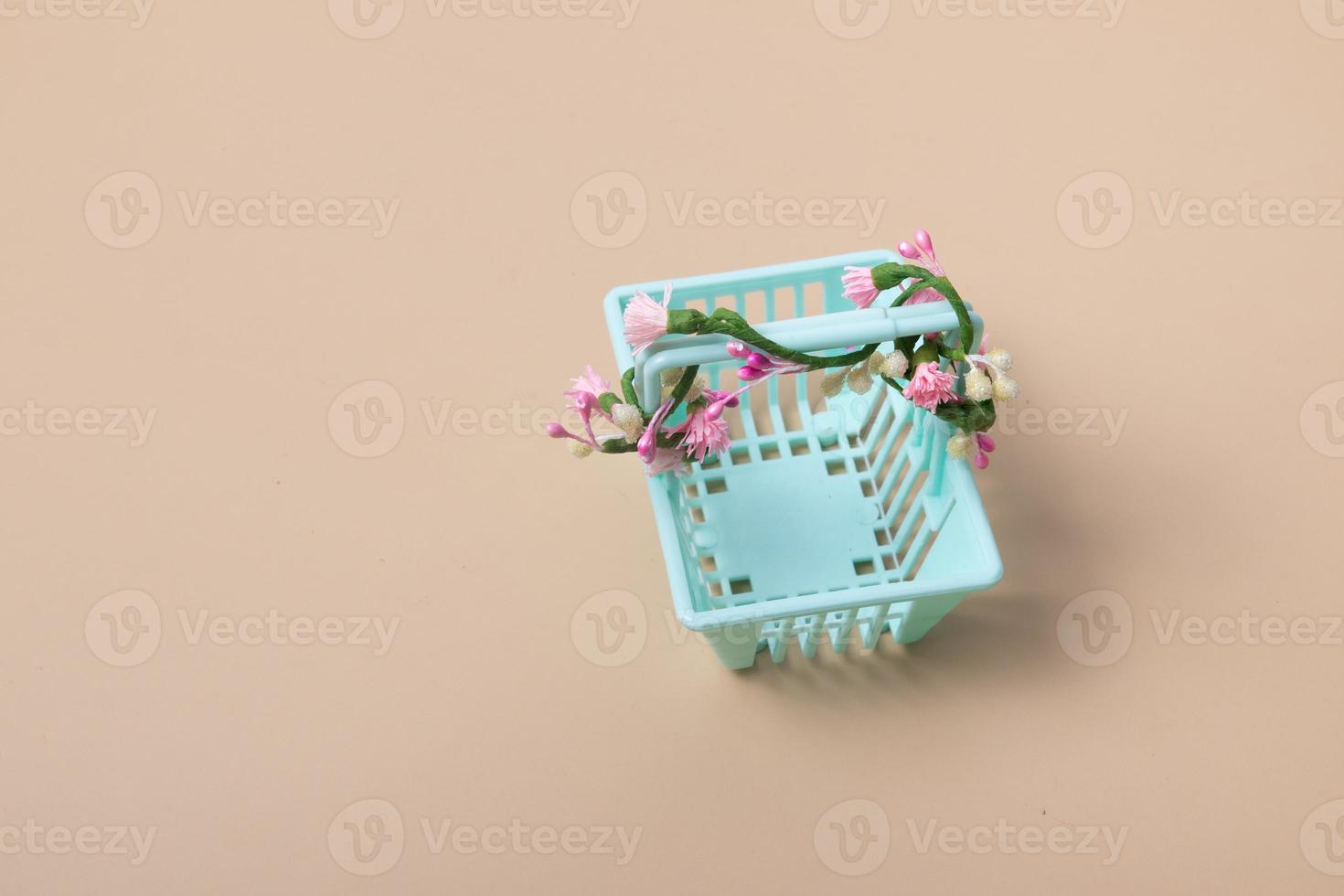 Empty shopping basket with flowers on a beige background. Minimalism. Spring sales, shopping, prices concept photo