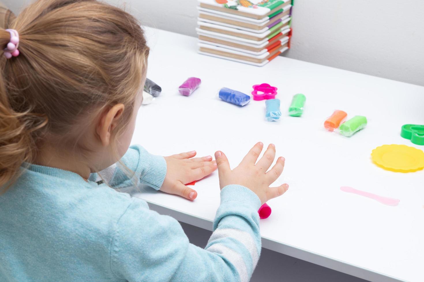 The girl at the table is playing with modeling dough. Childrens games for fine motor skills photo