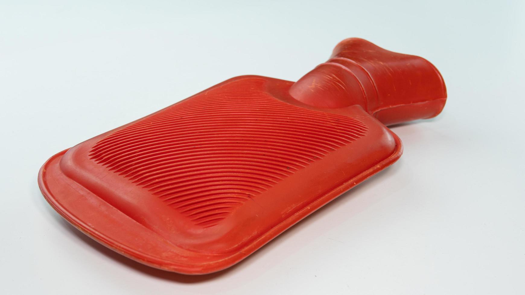Red hot water bag for compressing Relieve muscle injuries or keep warm. Place it on a white background. A device for holding hot water. To compress before physical therapy. photo