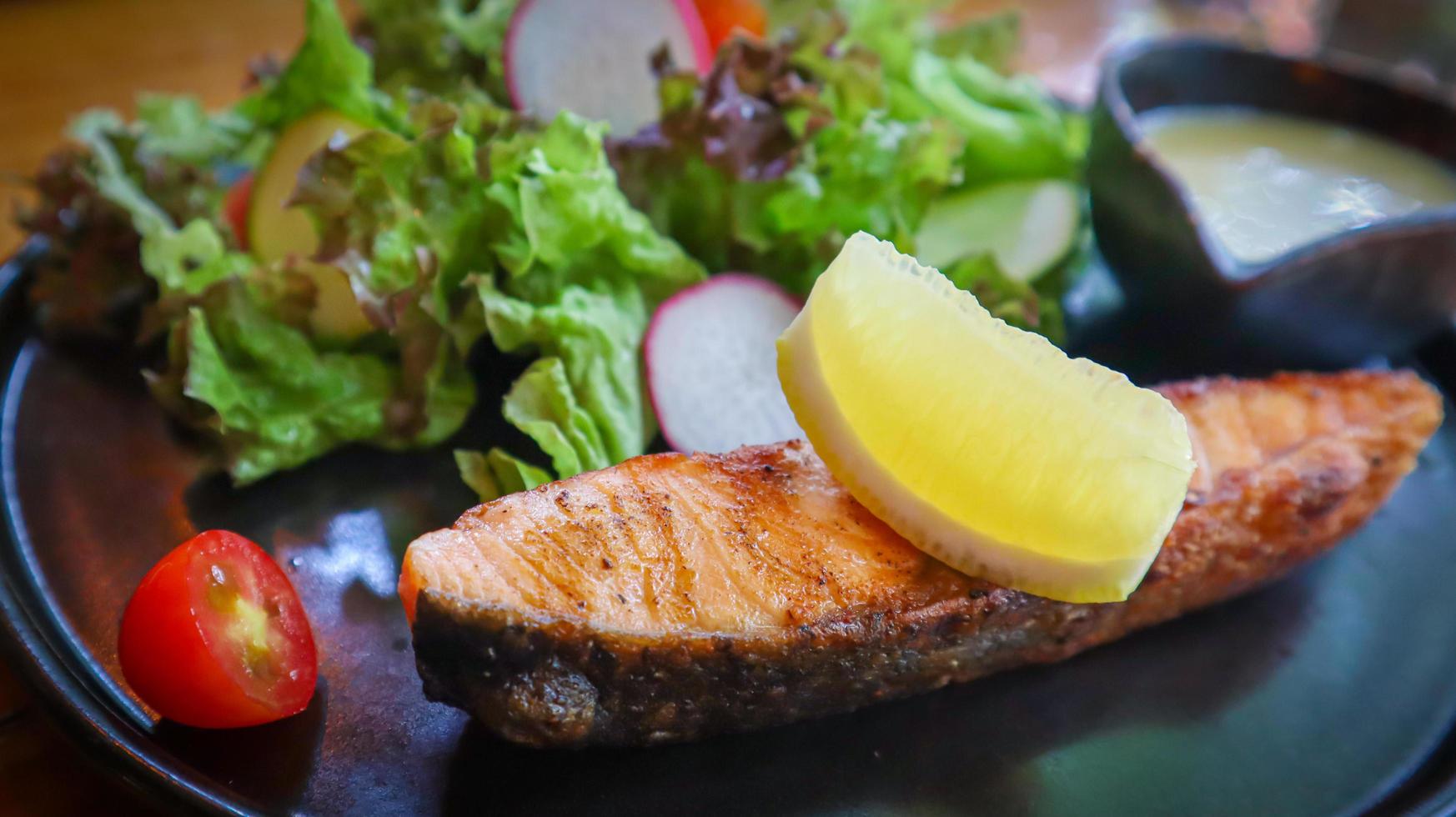 Grilled salmon fillet served with mixed green salad and keto cream salad dressing. photo