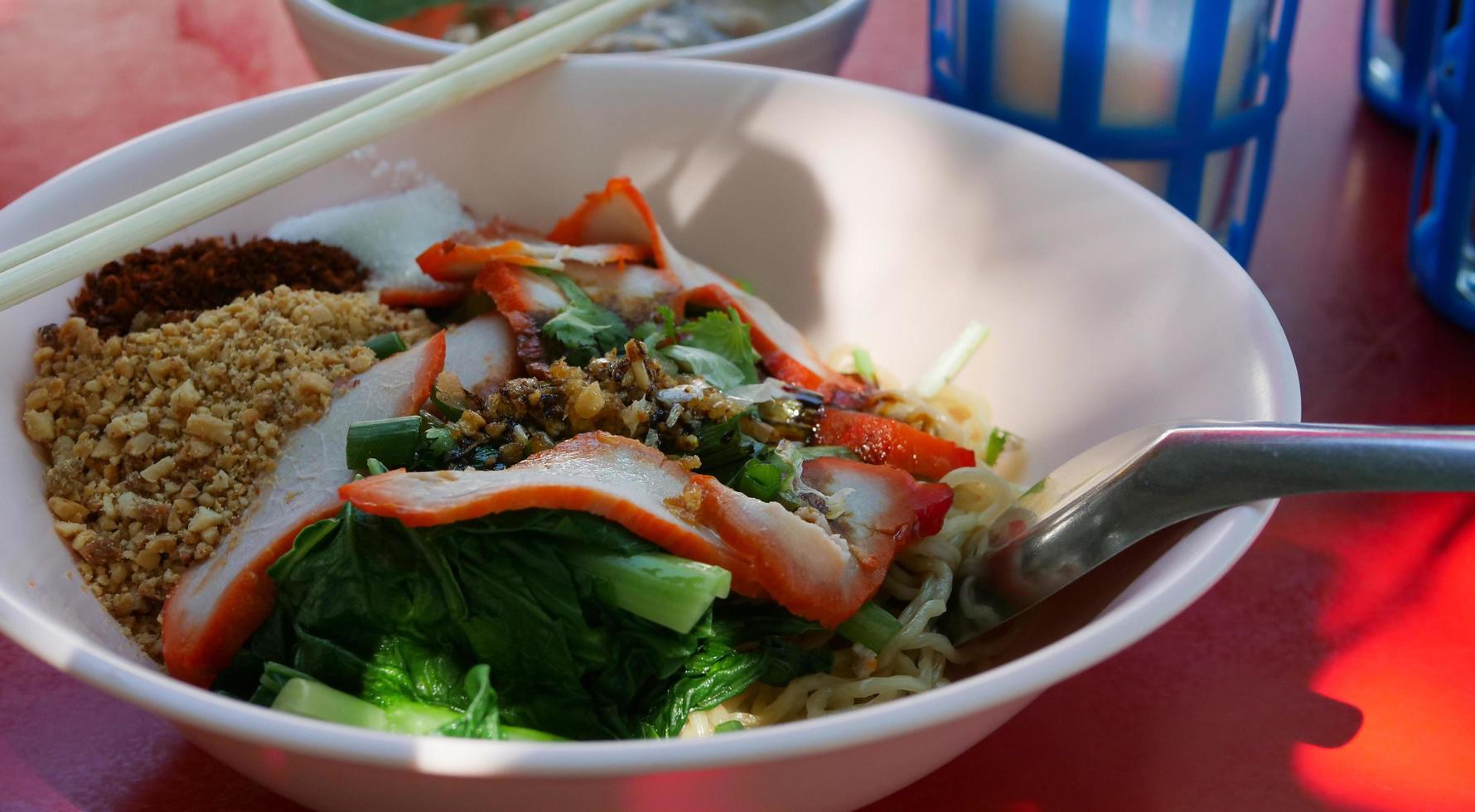 Dry red pork noodles. Yellow Noodles and Boiled Vegetables Topping with Roasted Pork. Famous Street Food in Thailand. photo