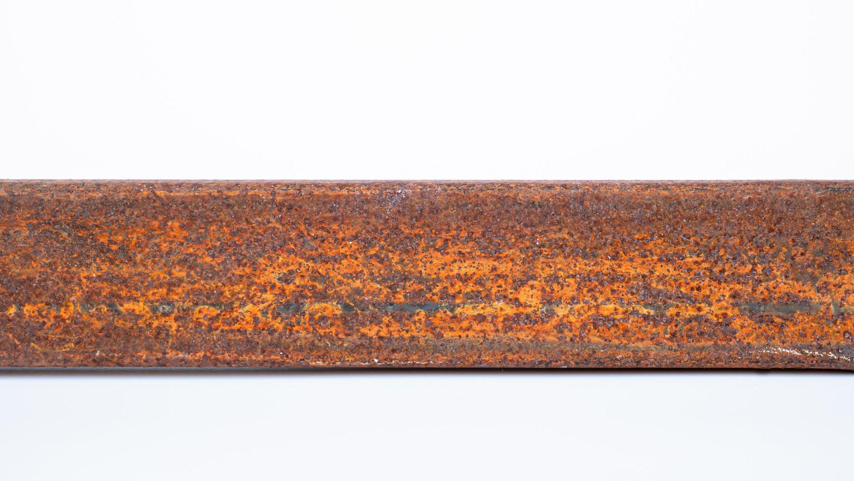 The rusted metal rod is full of the surface. Dirty iron rod placed on the floor and white background. photo