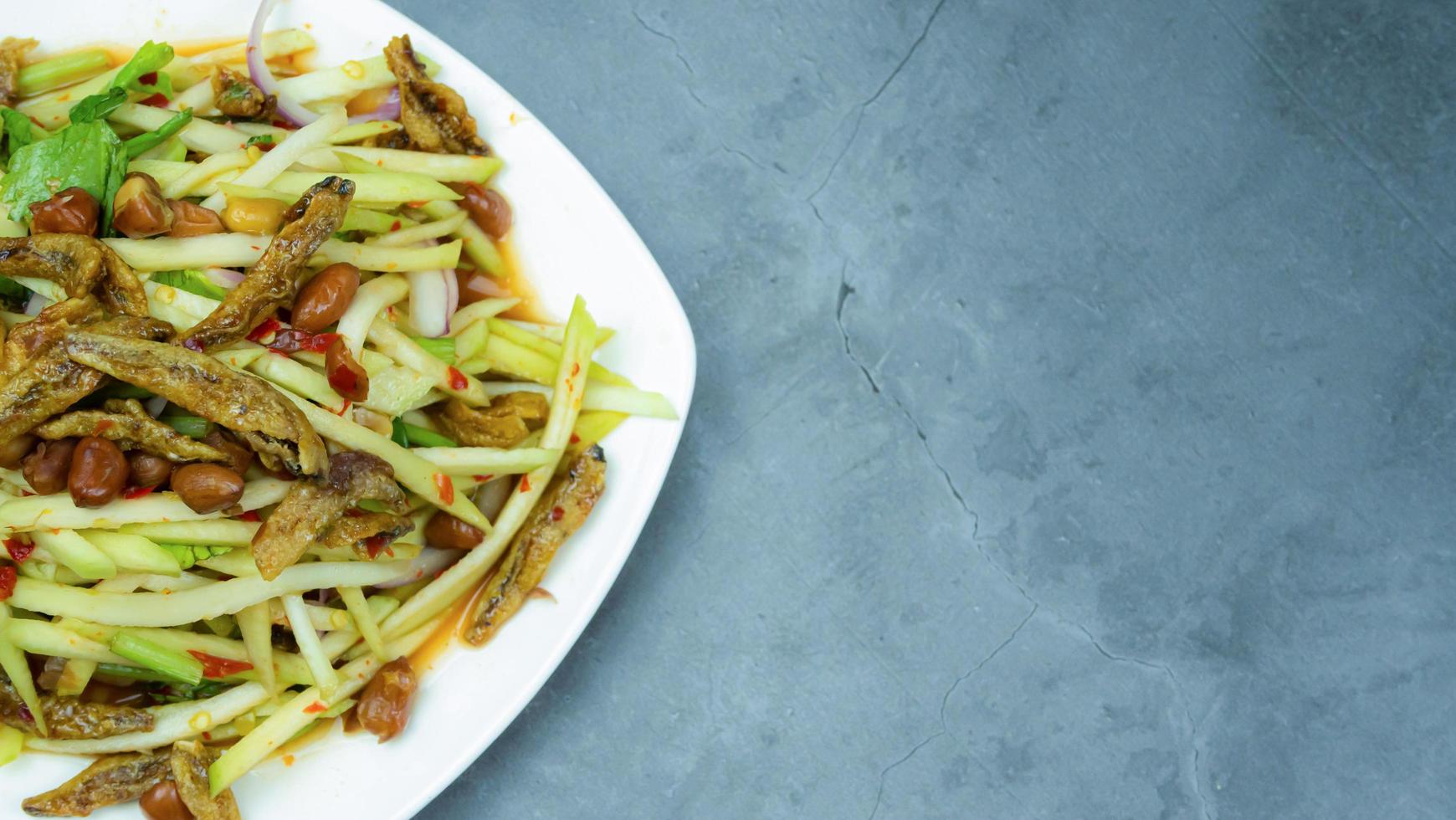 Yum, mango photo top views Food arrangement. Spicy salad food, topped with fried nuts and crispy fish. The main ingredients are raw mango, lime juice, fresh chili powder, fish sauce, sugar to mix.