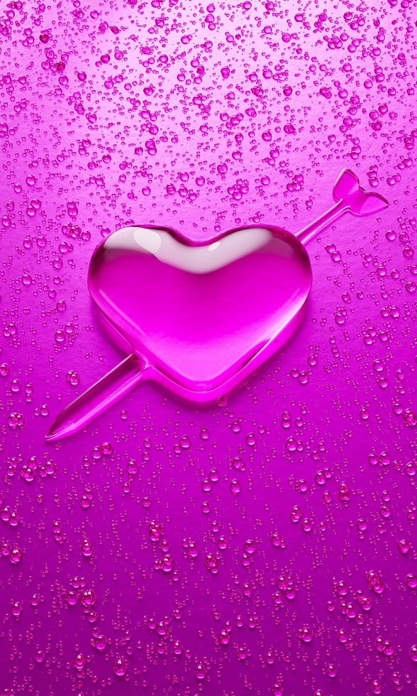 gotitas de agua en forma de corazón con flecha bordada en el significado del amor. un montón de gotas en superficies metálicas en tonos rosa y rosa oscuro para fondo móvil o papel tapiz. representación 3d. foto