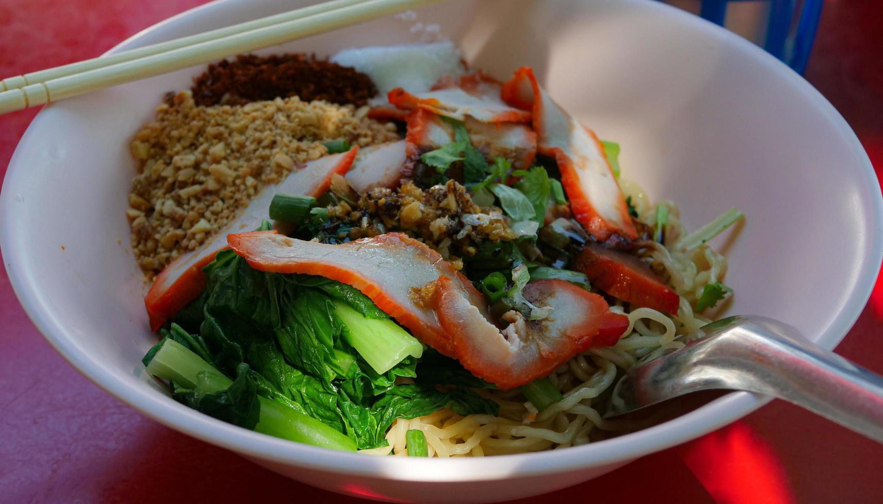 Dry red pork noodles. Yellow Noodles and Boiled Vegetables Topping with Roasted Pork. Famous Street Food in Thailand. photo