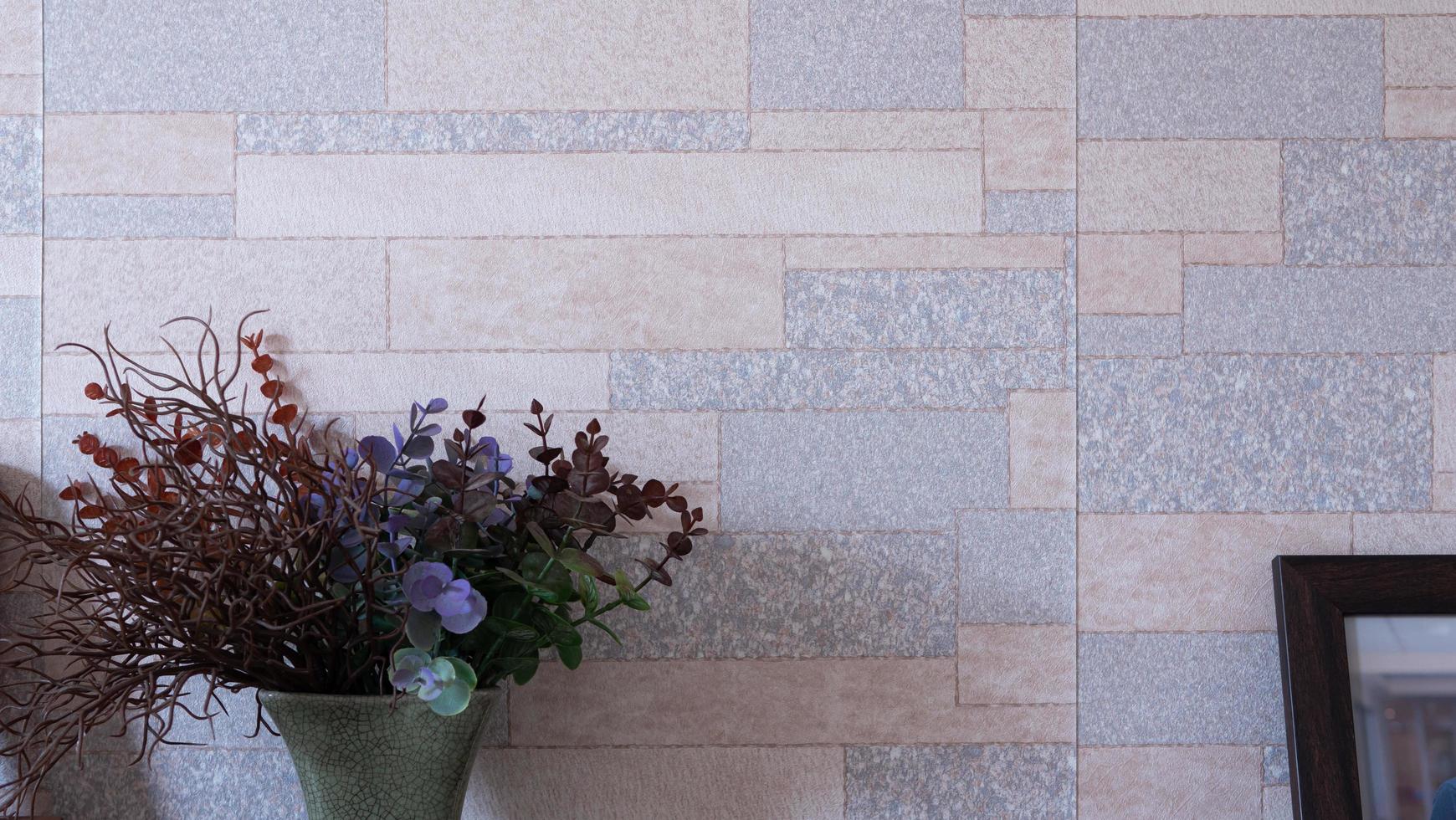 The fake plants and flowers in pots are placed in front of the wall of marble with a mixture of light blue and purple. The wall pattern, wallpaper or background is a grid. photo