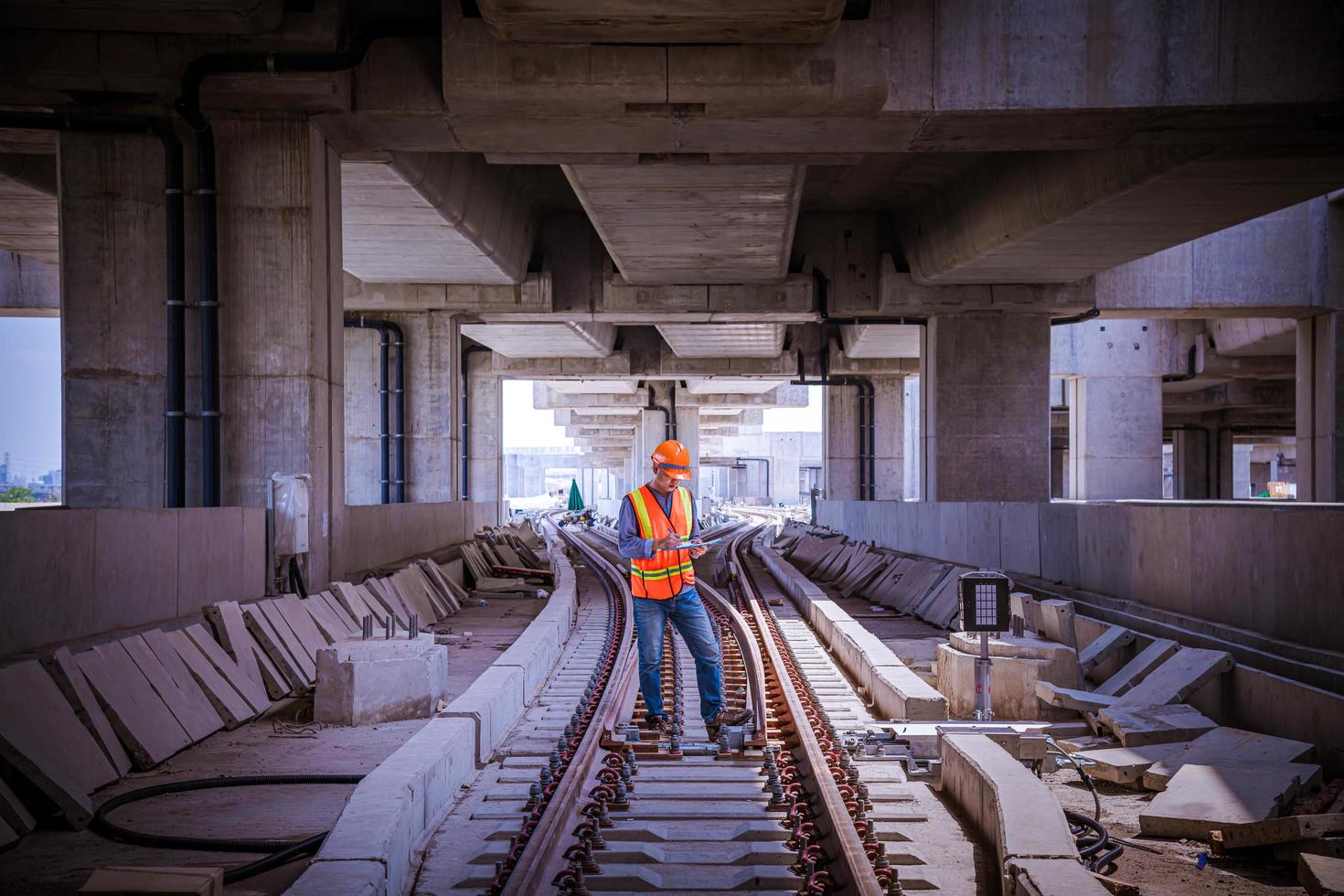 ingeniero ferroviario bajo control del proceso de construcción prueba de trenes y control del trabajo ferroviario en la estación de ferrocarril con comunicación por radio. ingeniero con uniforme de seguridad y casco de seguridad en el trabajo. foto