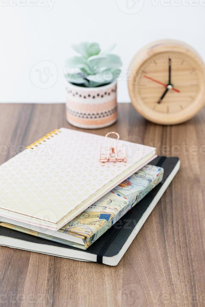 Feminine, girly themed workspace with pink ring notebook and black cover sketchbook on wooden table top. Time management concept. photo