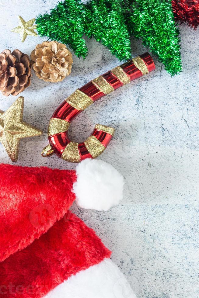 fondo de navidad en la vista superior con bastón de caramelo, conos de pino, estrella brillante y sombrero de santa claus. foto