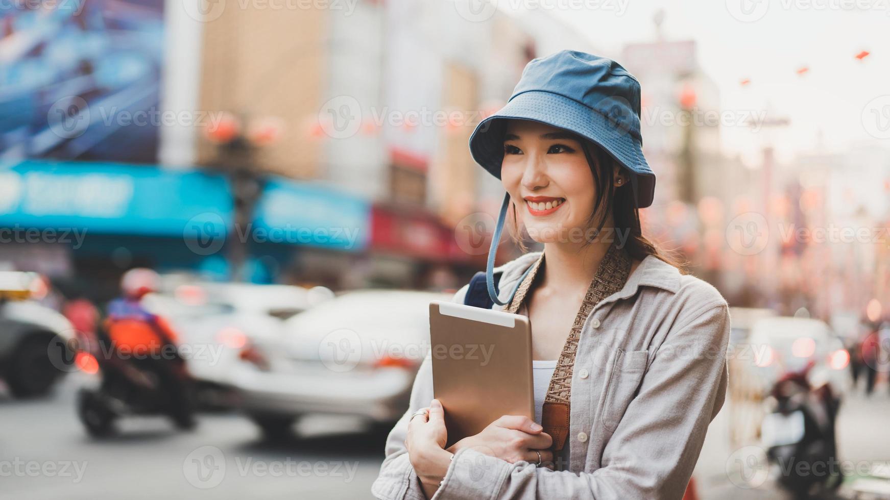 Solo young adult asian woman traveller wear blue hat and backpack travel with modern technology at outdoor on day. photo