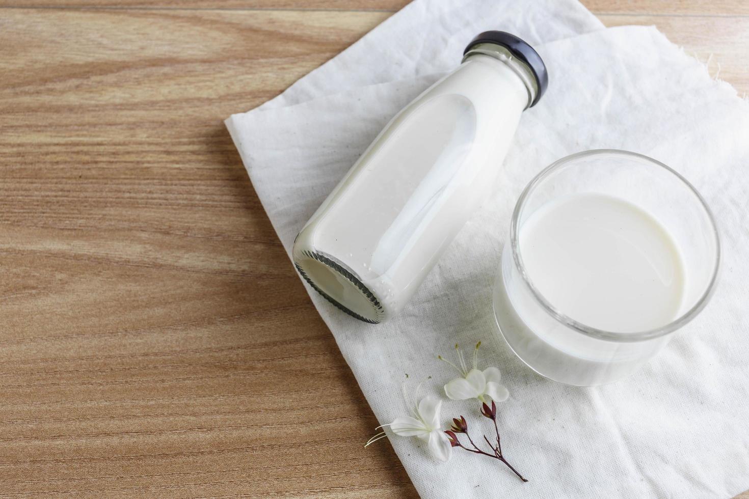 botella de leche y vaso de leche en la mesa de madera foto
