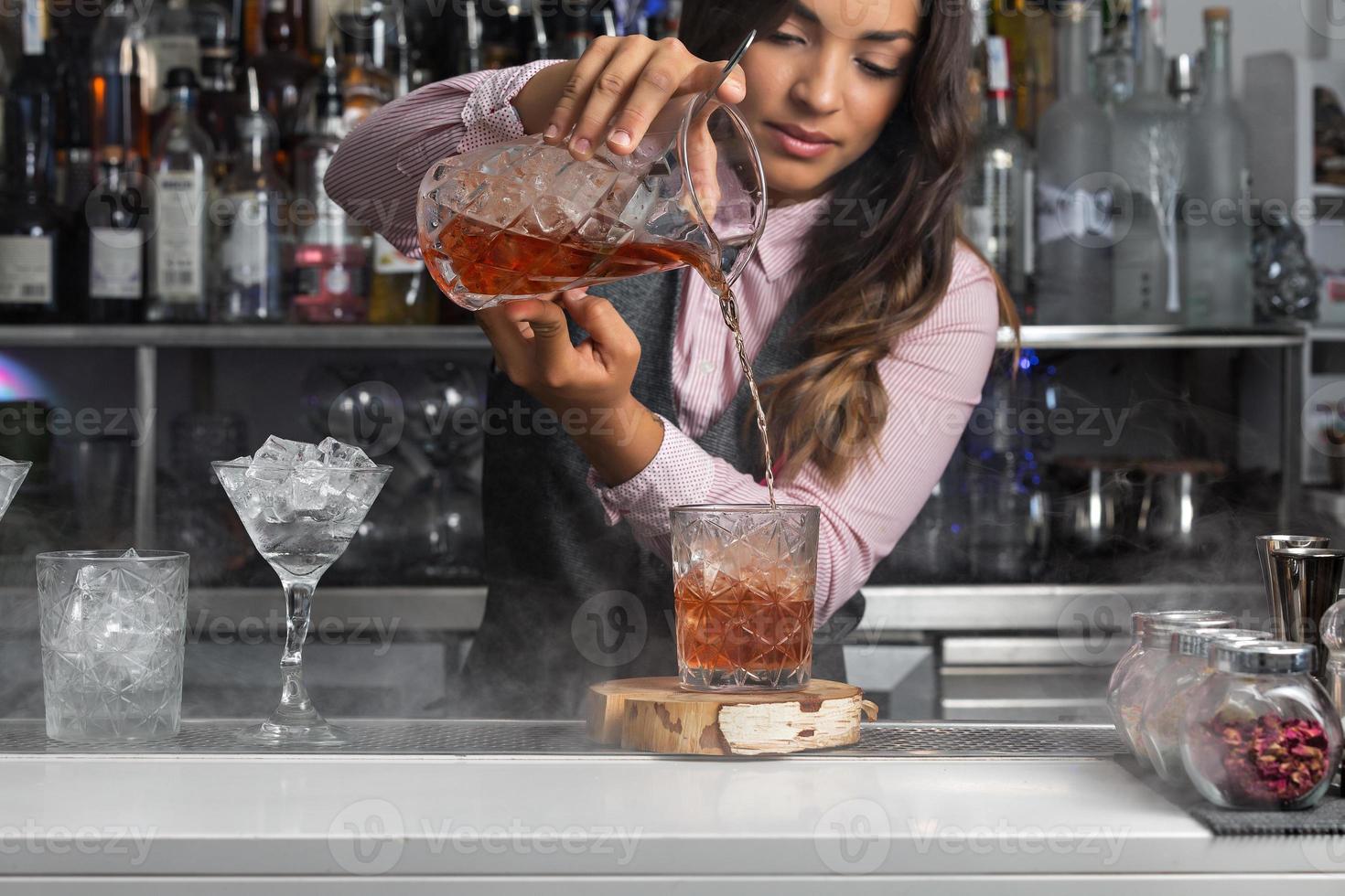 mujer preparando un cóctel en el mostrador del bar foto