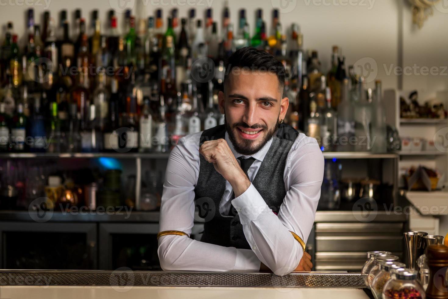 barman sonriente parado en la barra del bar foto