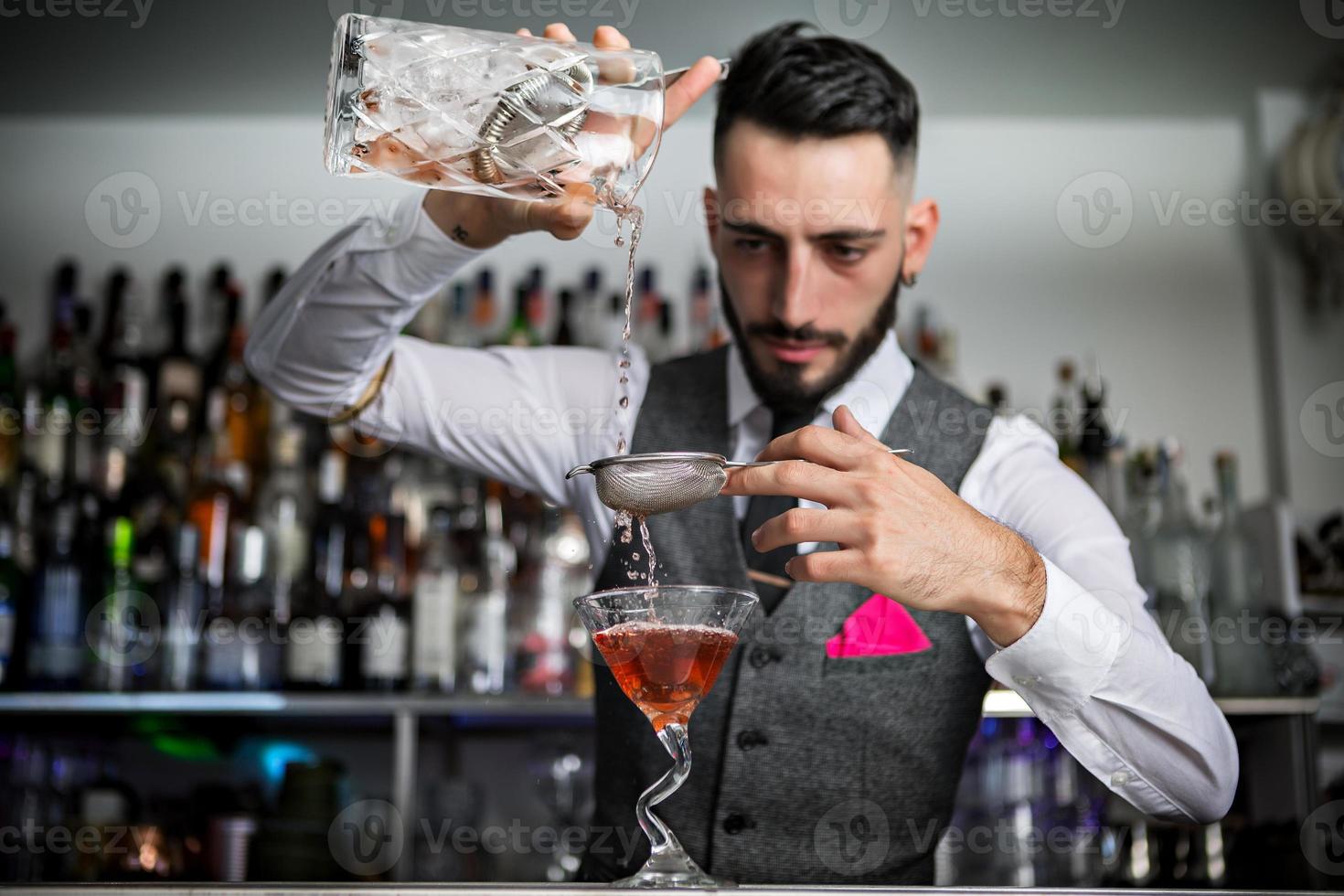 camarero con tamiz vertiendo bebida en vaso foto