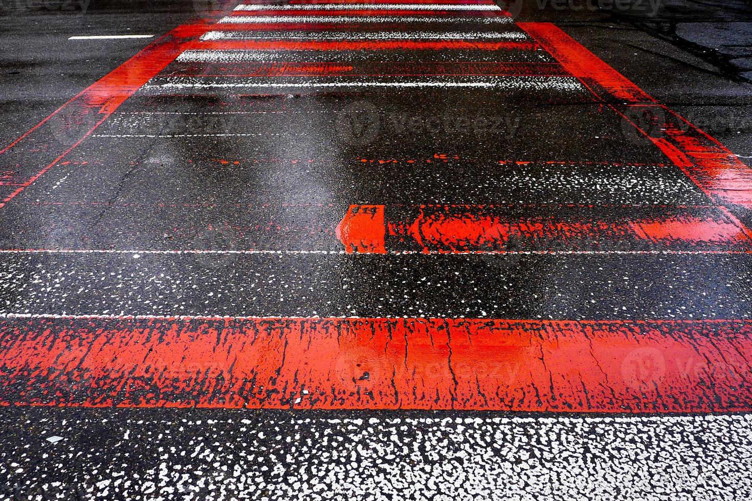 Wet asphalt road with red and white zebra crossing stripes. photo