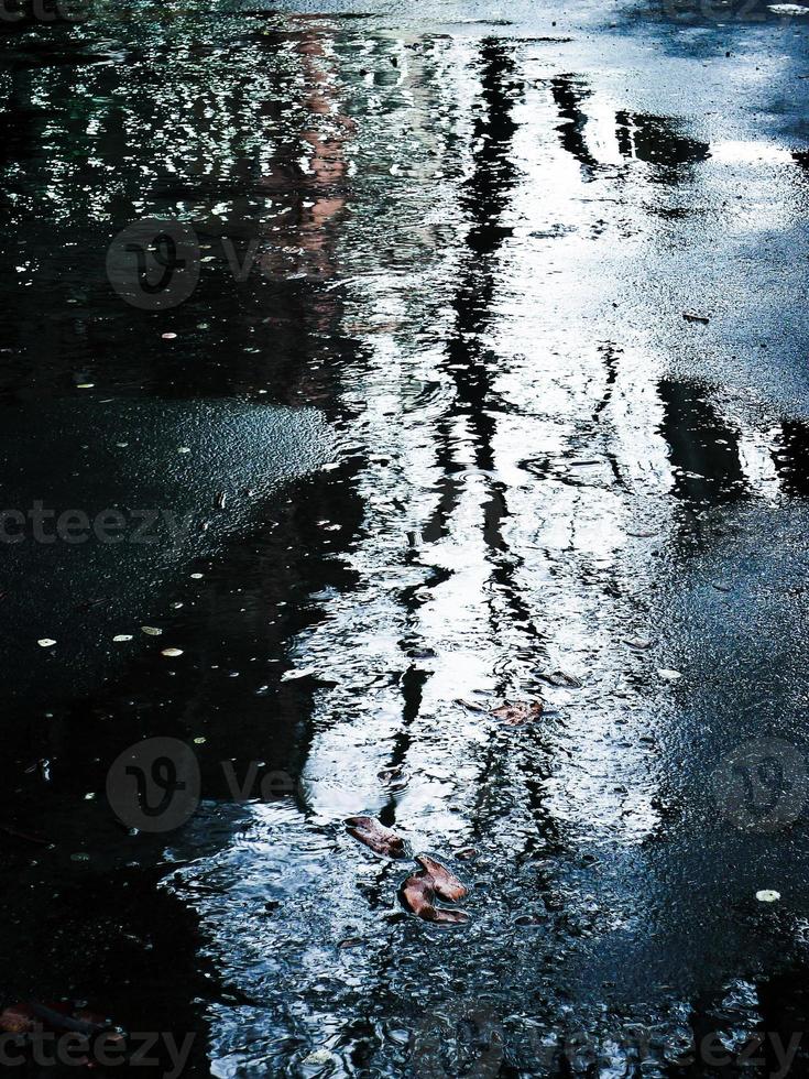 A blurry image of a tree silhouette reflected on water surface. photo