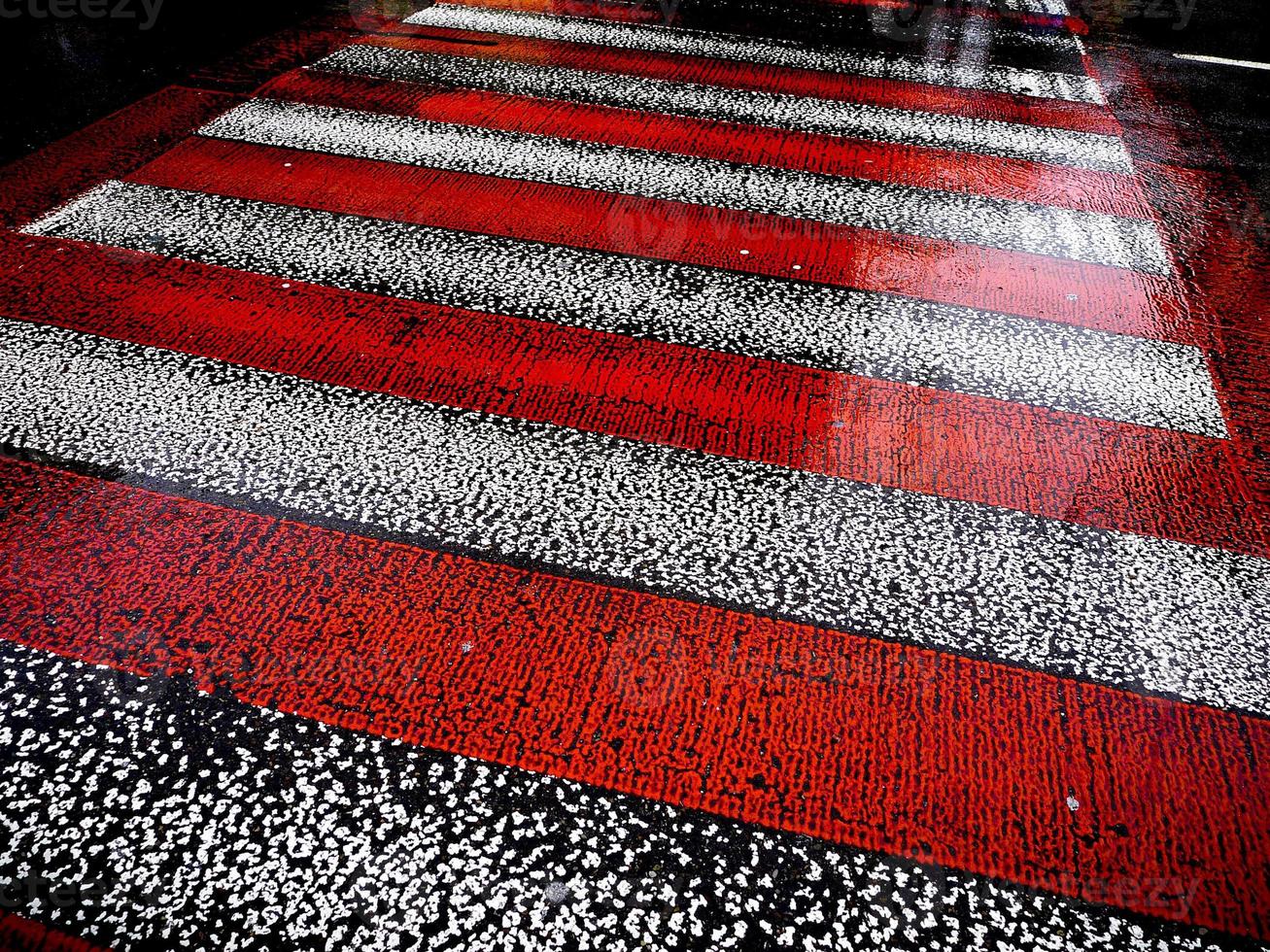 Wet asphalt road with red and white zebra crossing stripes. photo