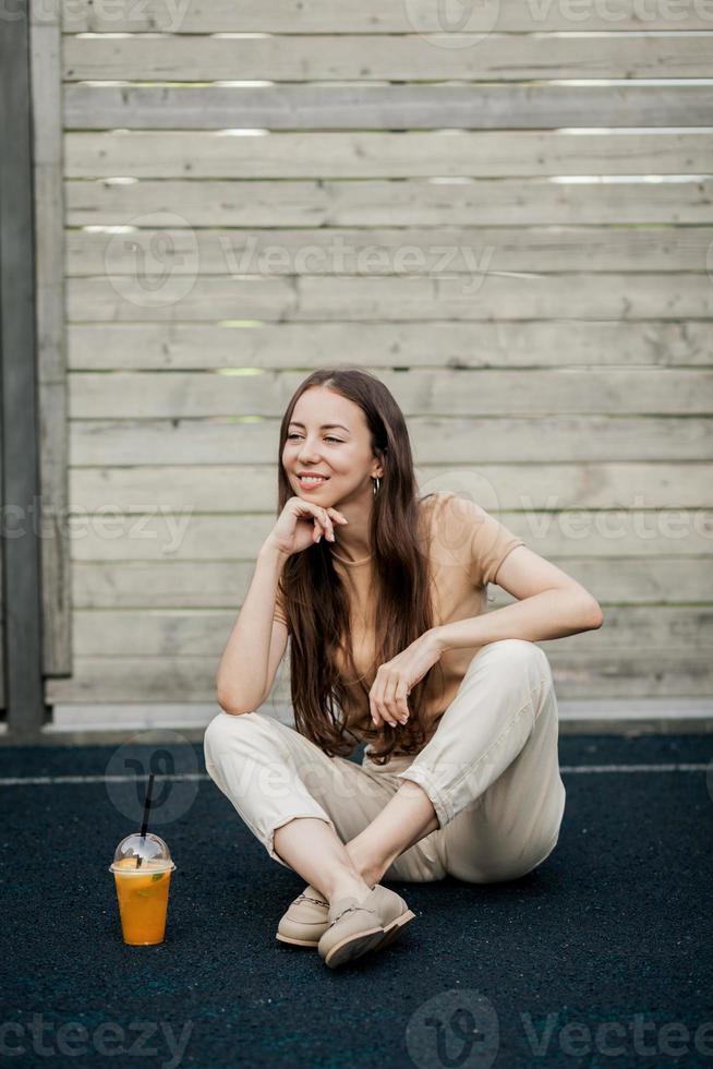 stylish woman sitting on street with juice photo