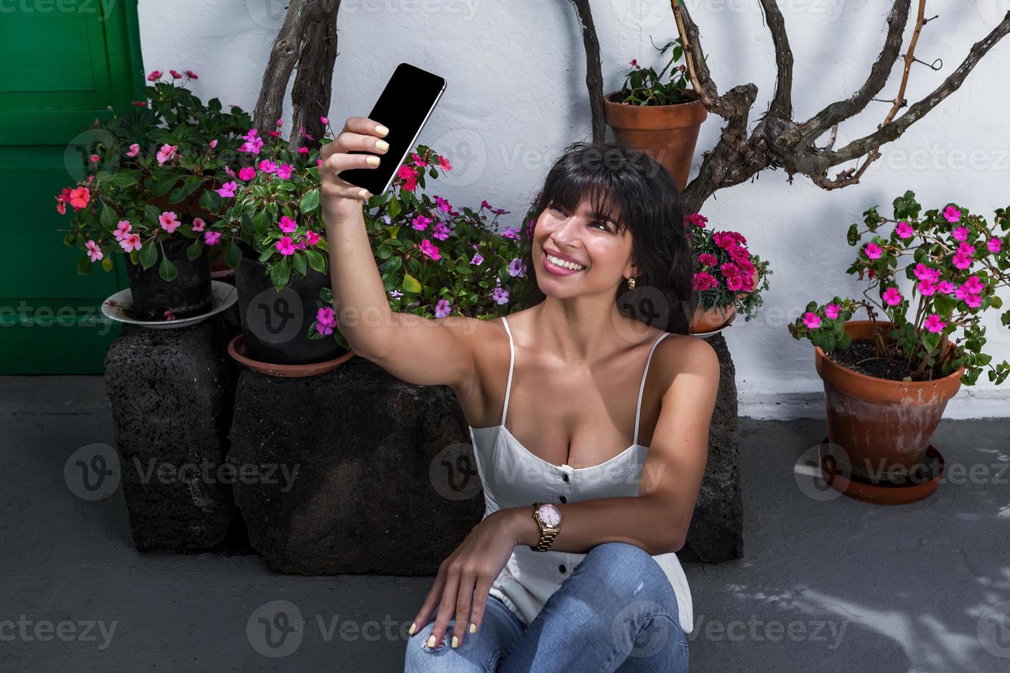 Happy Hispanic woman taking selfie near potted flowers photo