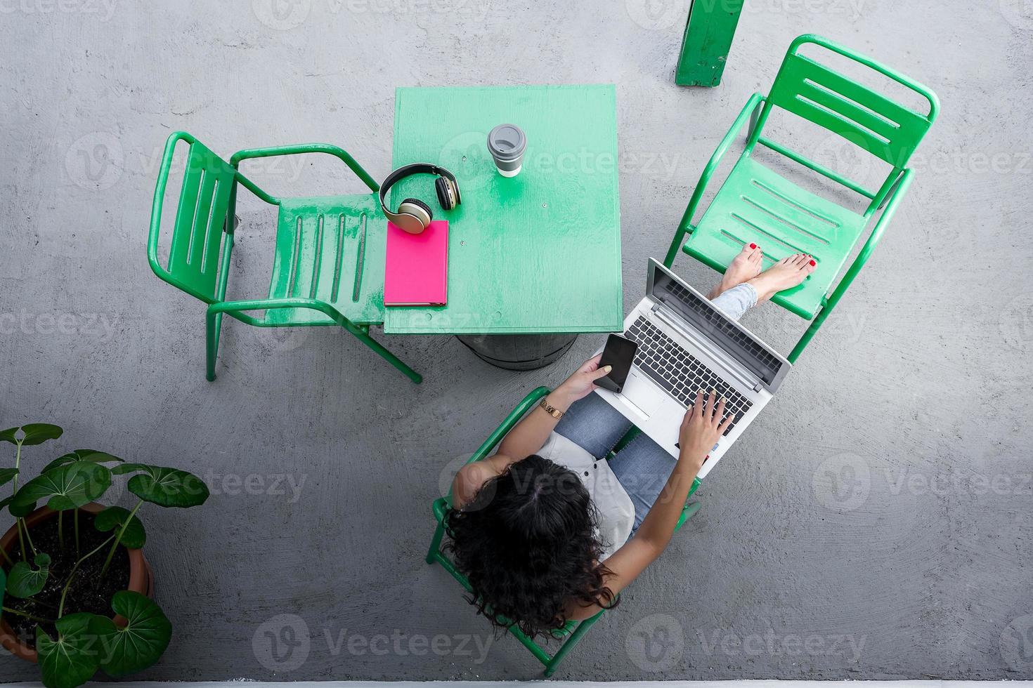 Unrecognizable freelancer with smartphone and laptop on terrace photo
