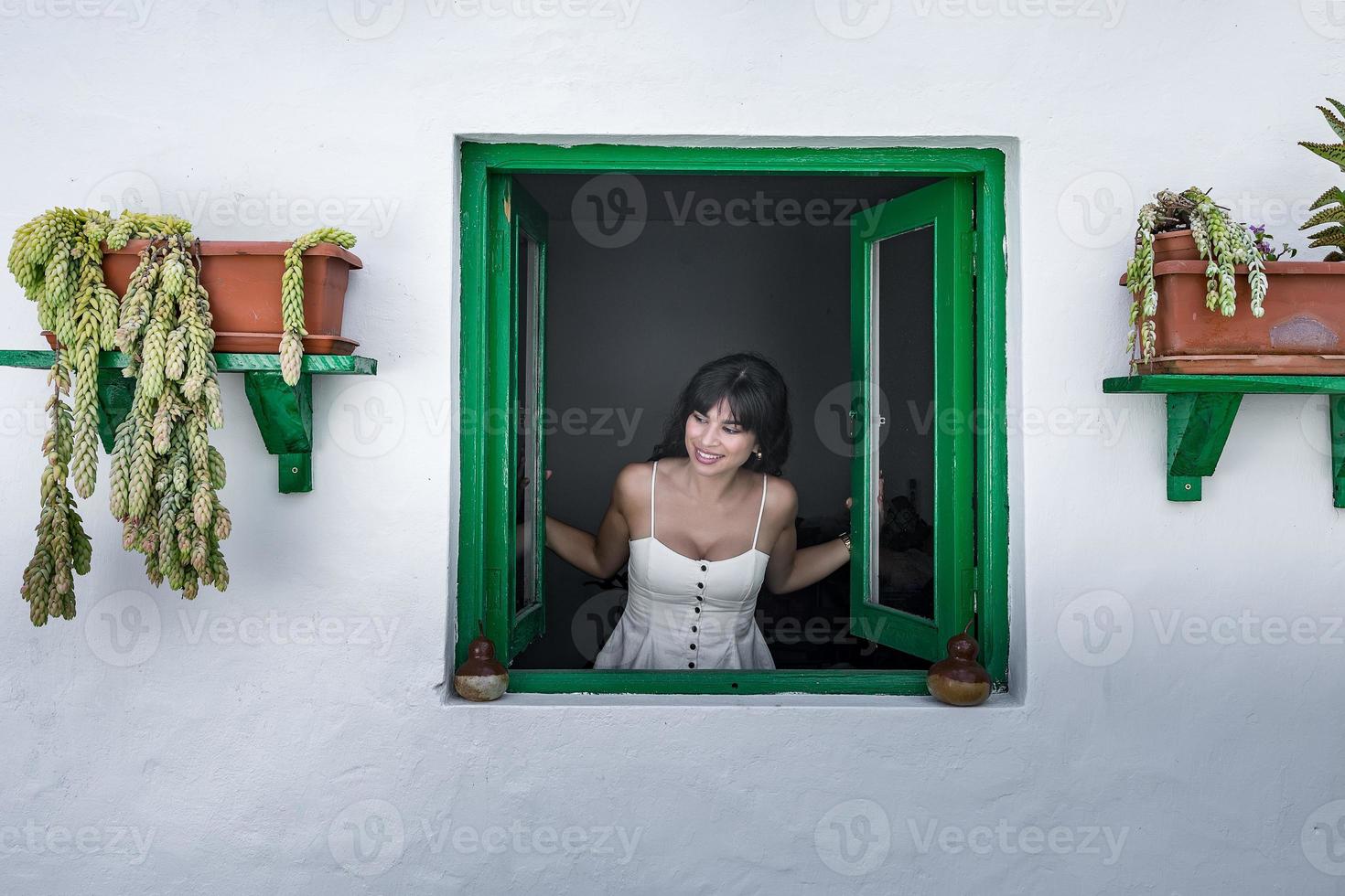 Happy ethnic lady opening window photo