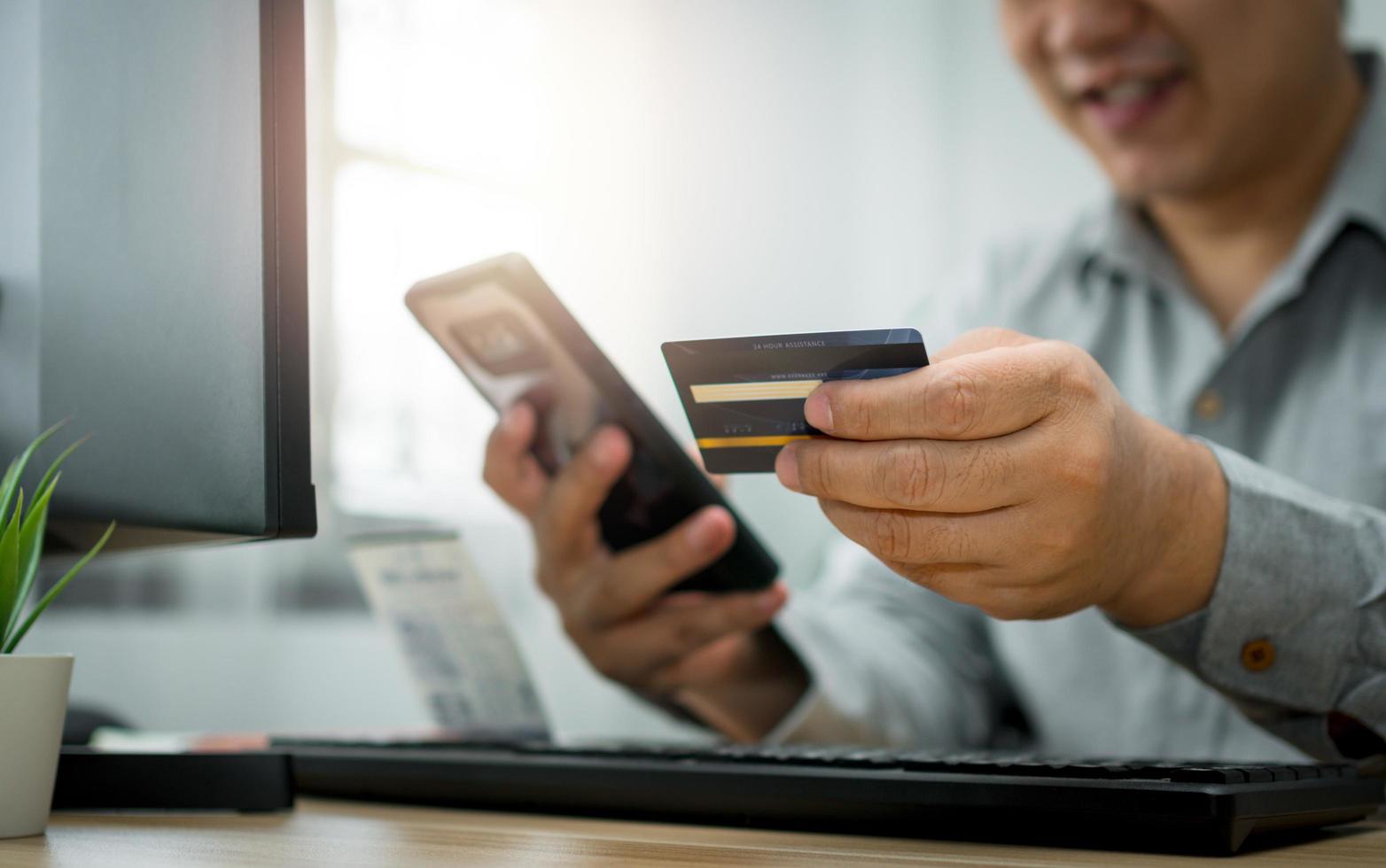 un hombre que tiene una tarjeta de crédito y usa un teléfono inteligente para pagar en línea para comprar después de ordenar productos a través de Internet. el concepto de tecnología para el comercio electrónico foto