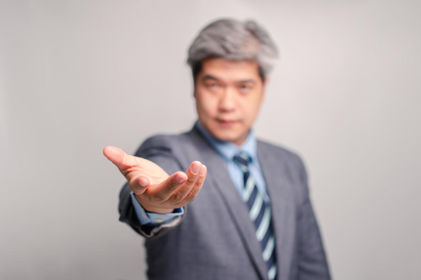 Selective focus of palm hand, of Asian senior businessman in a suit on white background isolated background. The concept of connection, technology, and corporation photo